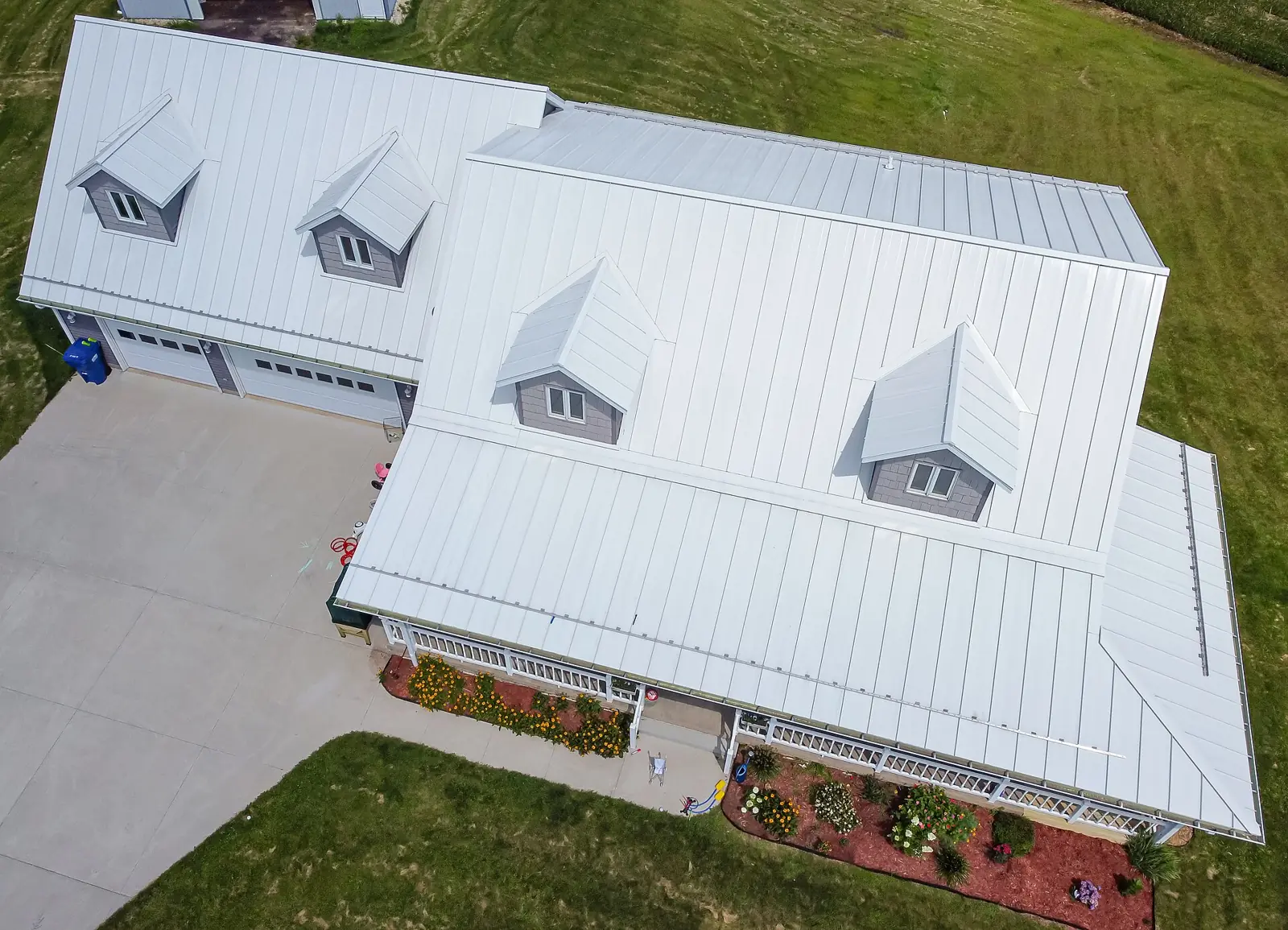 Aerial view of a white house with a standing-seam metal roof.