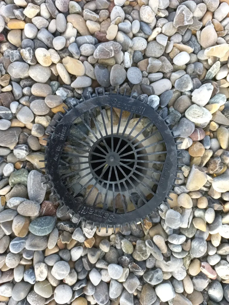 Flat-roof rainwater outlet surrounded by gravel.