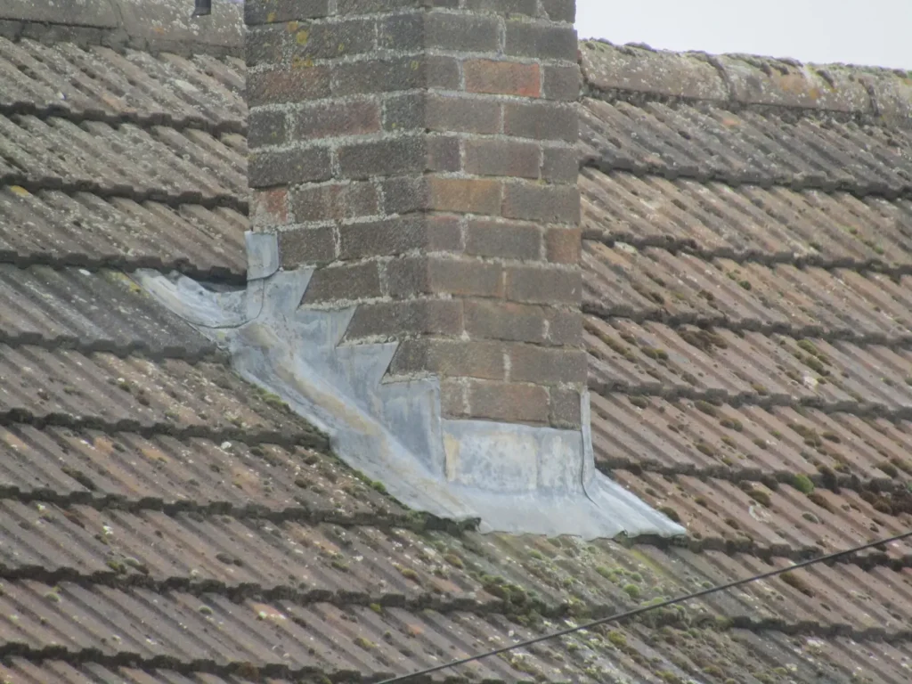 Lead flashing around a brick chimney stack.
