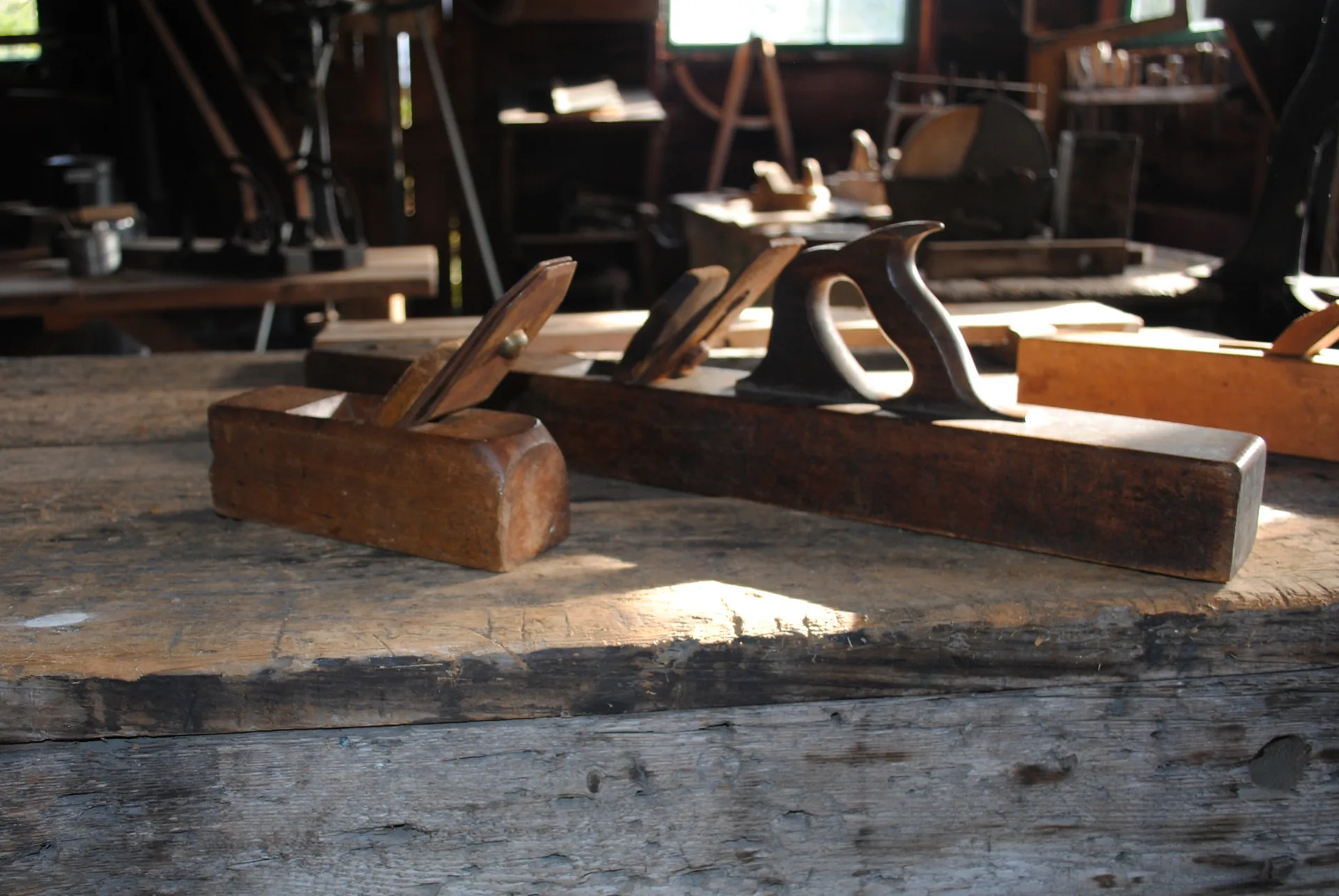 Hand planes on a timber workbench in side light.