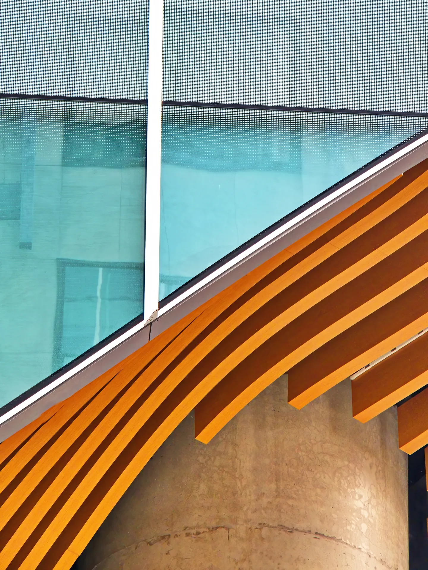 Angled orange members, pale concrete and glazed facade panels.